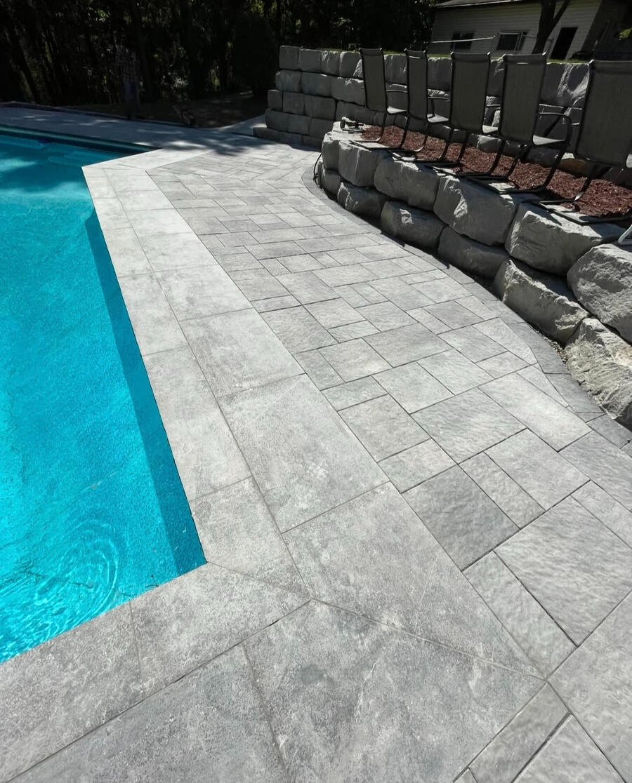 Light stone pool deck with structured layout and seating.