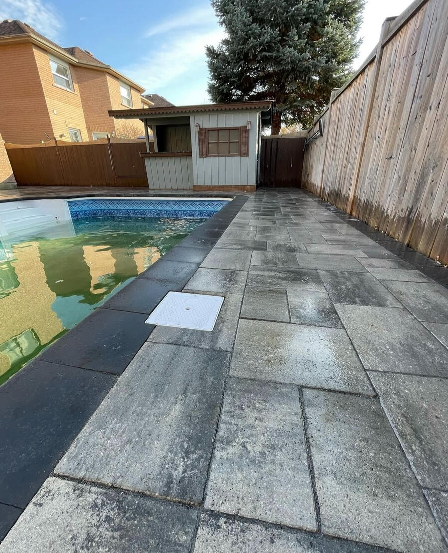 Narrow interlock walkway between pool and fence in Whitby backyard.