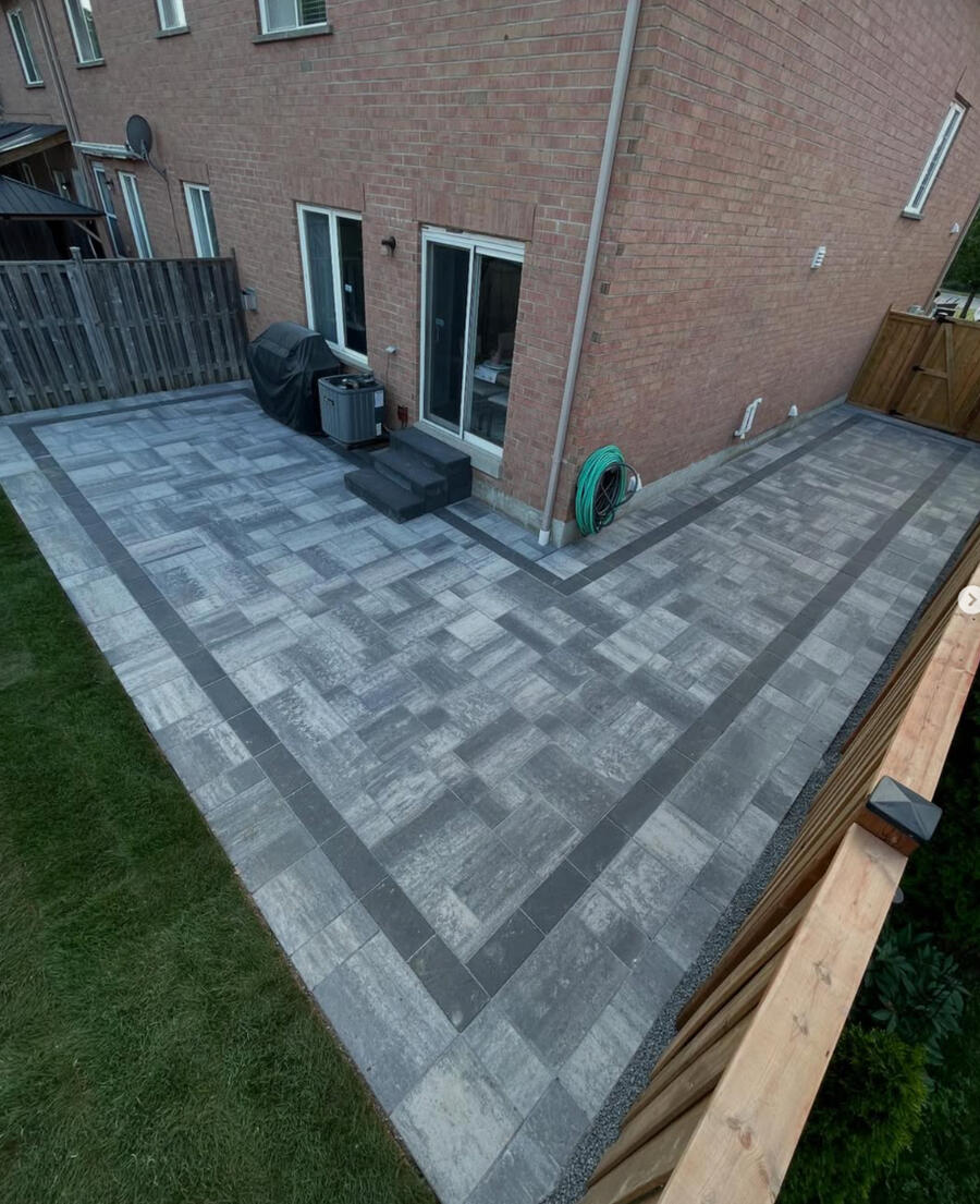L-shaped backyard interlock patio with darker border in Whitby.